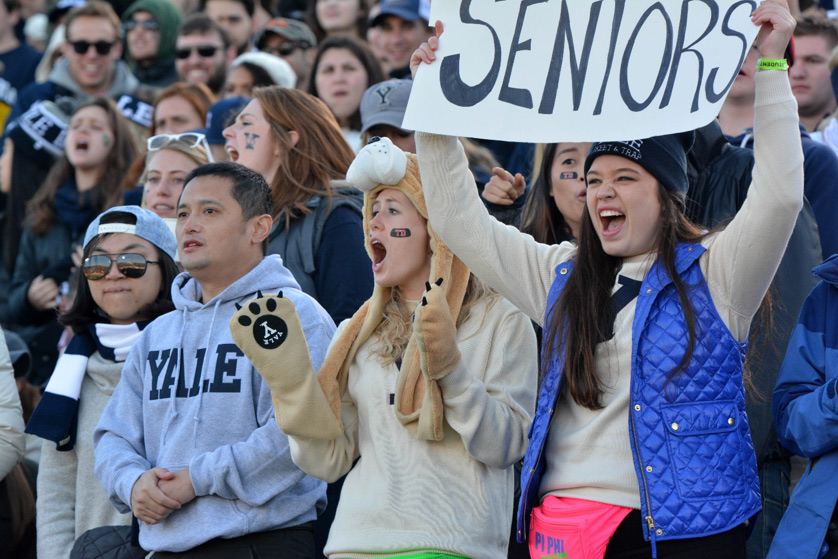 A crowd of people watching a game wearing a variety of Yale attire